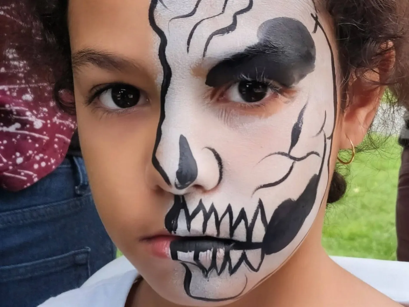 A child wearing a half-skull face-painting design